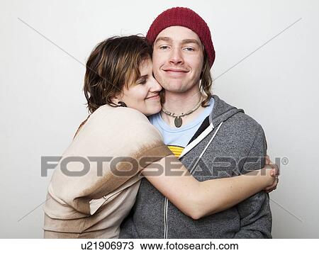 Stock Image - Studio Shot of young woman embracing young man. Fotosearch