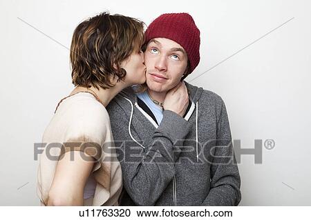Studio Shot of young woman kissing young man View Large Photo Image Stock Image - Studio Shot of young woman kissing young man. Fotosearch