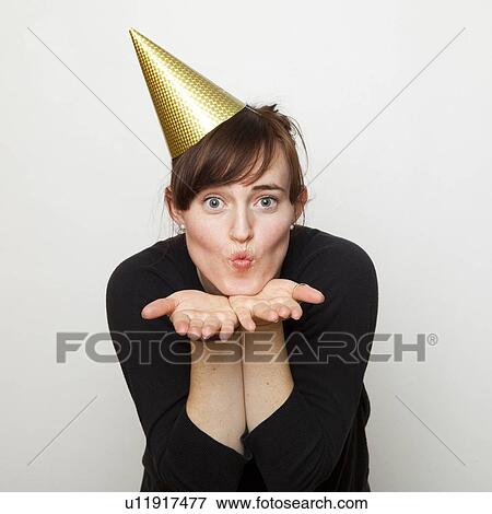 Studio Shot of young woman party hat blowing kiss View Large Photo Image Stock Photo - Studio Shot of young woman party hat blowing kiss. Fotosearch