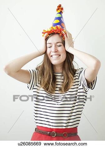 Stock Photo - Studio shot of young woman wearing party hat. Fotosearch