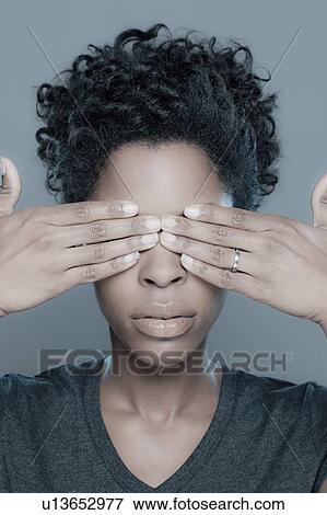 Stock Photo - Studio shot of young woman with hands covering eyes. Fotosearch