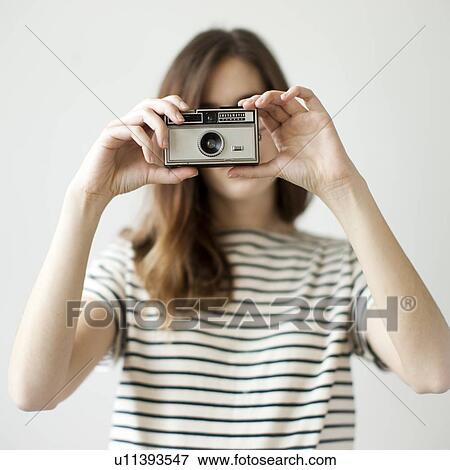 Stock Photo - Studio shot of young woman with old-fashioned camera. Fotosearch