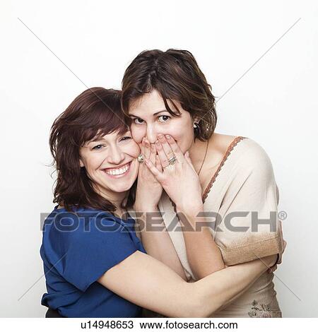 Studio Shot portrait of young women embracing, covering mouth with hand View Large Photo Image Stock Image - Studio Shot portrait of young women embracing, covering mouth with hand. Fotosearch