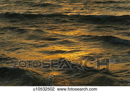 Stock Image - Surface of water at sunset. Fotosearch