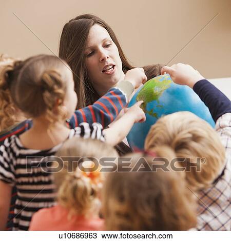 Stock Image - Teacher with children (2-3, 4-5) learning geography. Fotosearch