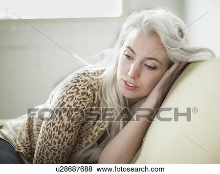 Stock Photo - Thoughtful young woman sitting on sofa. Fotosearch