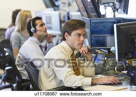 Stock Photo - Traders at trading desk. Fotosearch