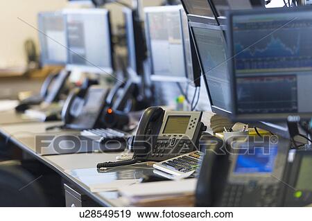 Stock Photo - Trading desk with computers and phones. Fotosearch