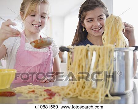 Stock Photo -  Two girls cooking pasta. Fotosearch