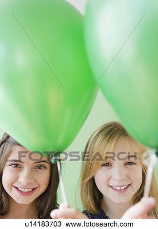 Two girls holding green balloons View Large Photo Image Stock Image - Two girls holding green balloons. Fotosearch