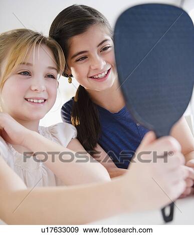 Stock Photo -  Two girls looking at mirror. Fotosearch