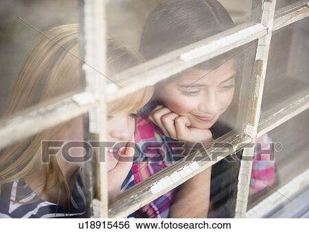 Stock Photograph - Two girls looking through window. Fotosearch