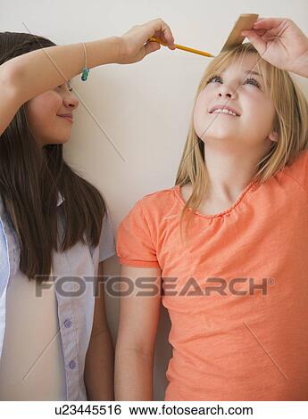 Stock Photograph - Two girls measuring height. Fotosearch