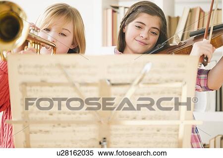 Two girls playing instruments from sheet music View Large Photo Image Stock Photography - Two girls playing instruments from sheet music. Fotosearch