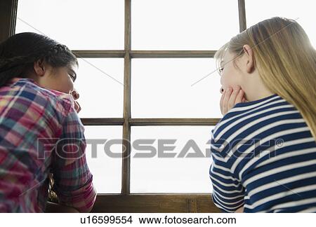 Picture - Two girls sitting by window. Fotosearch