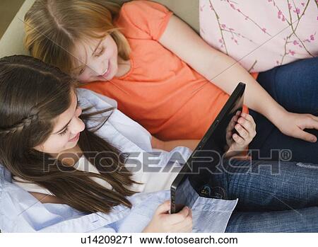 Two girls using digital tablet in bed View Large Photo Image Stock Image - Two girls using digital tablet in bed. Fotosearch