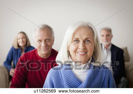 Stock Photo - Two senior couples on sofa, smiling woman in foreground. Fotosearch