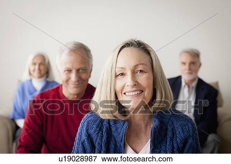 Stock Photo - Two senior couples on sofa, smiling woman in foreground. Fotosearch
