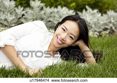 View of smiling woman lying on lawn View Large Photo Image Picture - View of smiling woman lying on lawn. Fotosearch
