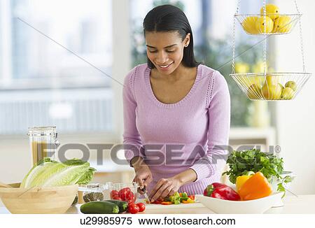 Stock Photography - Woman chopping vegetables in kitchen. Fotosearch