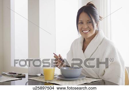 Picture - Woman in bathrobe having cereal for breakfast. Fotosearch