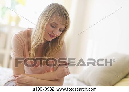 Stock Image - Woman leaning on bed. Fotosearch