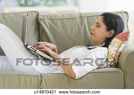 Woman lying on sofa using laptop View Large Photo Image Stock Image - Woman lying on sofa using laptop. Fotosearch