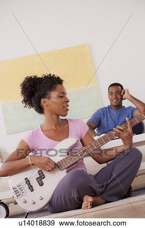 Woman playing electric guitar, man in background View Large Photo Image Stock Photo - Woman playing electric guitar, man in background. Fotosearch