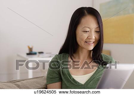 Stock Photography - Woman reading e-book at home. Fotosearch