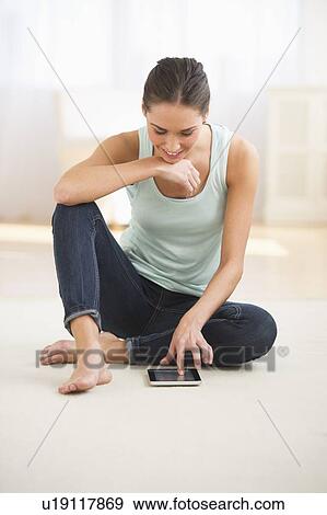 Stock Photo - Woman sitting on floor and using digital tablet. Fotosearch