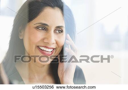 Stock Photograph - Woman talking on mobile phone behind glass wall. Fotosearch