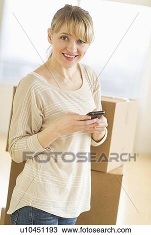 Stock Image - Woman using smart phone during relocation. Fotosearch