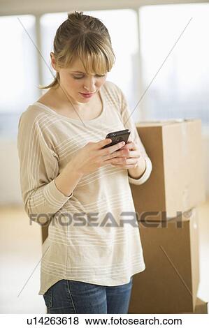 Stock Photo - Woman using smart phone during relocation. Fotosearch