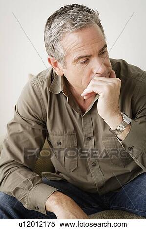 Worried mature man sitting on sofa View Large Photo Image Stock Photography - Worried mature man sitting on sofa. Fotosearch