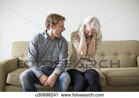 Young couple arguing while sitting on sofa View Large Photo Image Stock Image - Young couple arguing while sitting on sofa. Fotosearch