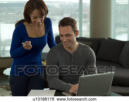Young couple paying bills at kitchen table View Large Photo Image Stock Photo - Young couple paying bills at kitchen table. Fotosearch
