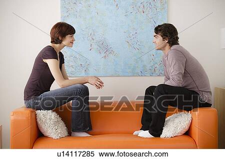 Young couple sitting on sofa and looking at each other View Large Photo Image Stock Photography - Young couple sitting on sofa and looking at each other. Fotosearch