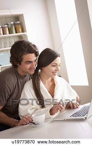 Stock Image - Young couple using laptop together. Fotosearch