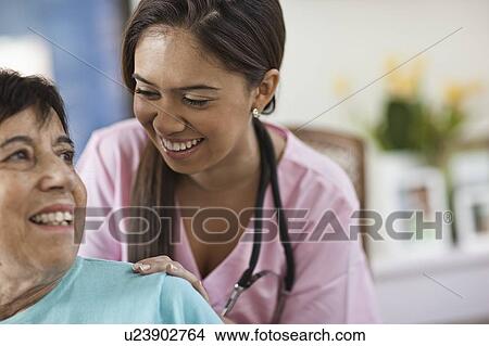 Picture - Young female nurse attending patient. Fotosearch