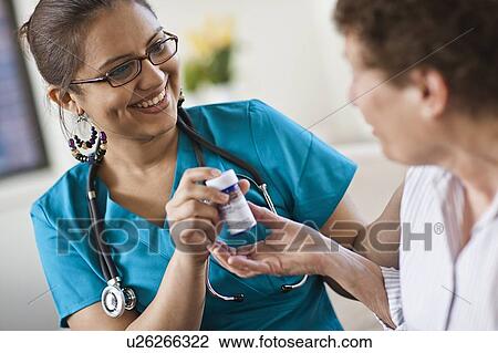 Young female nurse attending patient View Large Photo Image Stock Image - Young female nurse attending patient. Fotosearch