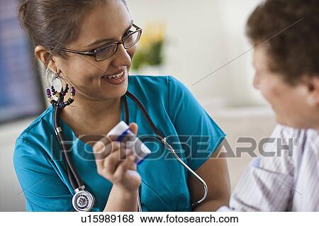 Young female nurse attending patient View Large Photo Image Stock Photo - Young female nurse attending patient. Fotosearch