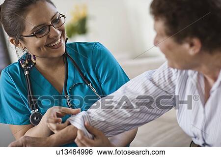 Young female nurse attending patient View Large Photo Image Stock Photograph - Young female nurse attending patient. Fotosearch