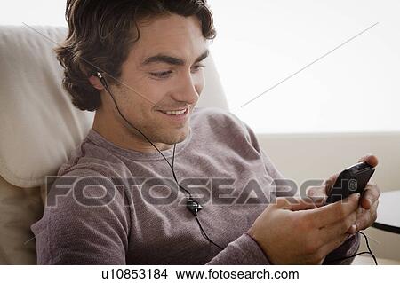 Young man listening music on armchair View Large Photo Image Picture - Young man listening music on armchair. Fotosearch
