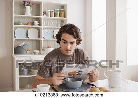 Young man reading newspaper at breakfast View Large Photo Image Stock Photo - Young man reading newspaper at breakfast. Fotosearch