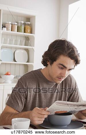 Young man reading newspaper at breakfast View Large Photo Image Stock Photography - Young man reading newspaper at breakfast. Fotosearch