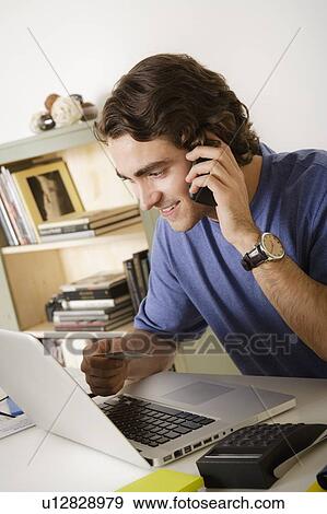 Stock Photo - Young man talking via mobile at home. Fotosearch