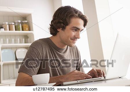 Stock Photography - Young man using laptop. Fotosearch