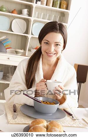 Stock Image - Young smiling woman at breakfast. Fotosearch