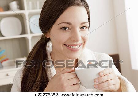 Stock Image - Young smiling woman holding cup. Fotosearch