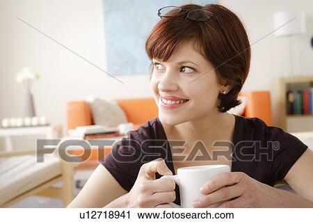 Young smiling woman holding mug and looking away View Large Photo Image Stock Image - Young smiling woman holding mug and looking away. Fotosearch